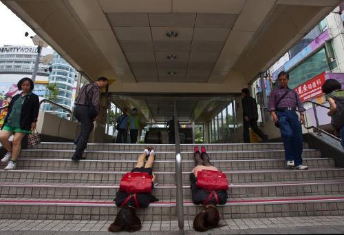 Karren and Jinyu, also known as the Pujie Girls, perform a plank on the staircase of a train station in Taipei, Taiwan.