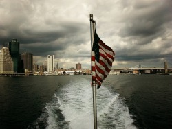 nythroughthelens:  The New York City skyline and the Brooklyn Bridge as seen from the East River on a stormy day. New York City. Buy “The United States Flag &amp; The New York City Skyline” Posters and Prints here, View my store, email me, or ask