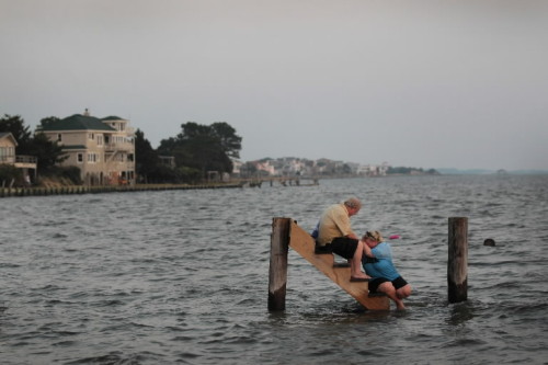 Billy Stinson comforts his daughter Erin as they sit on the steps where their cottage once stood in Nags Head, N.C., before it was destroyed by Hurricane Irene.
“We were pretending, just for a moment, that the cottage was still behind us and we were...