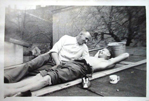 A vintage photo of two men laying on a rooftop together. 