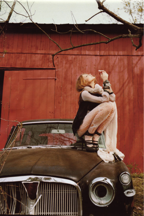 Torned white fishnet tights on top of an old automobile