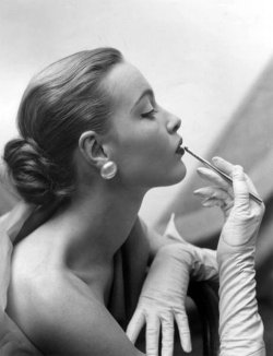 theniftyfifties:  A model applies lipstick, 1950s. 
