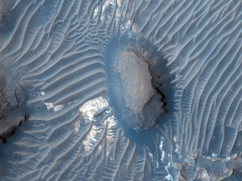 The photo above depicts a region of Mars as seen by HiRISE, a camera located on board the Mars Reconnaissance Orbiter. Prominent in the picture is a vast dune field which is formed through mechanics known as Aeolian Processes. Basically, a fancy word...