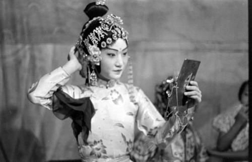 legrandcirque:A Chinese opera performer checking her hair and makeup in a mirror. Photograph by Carl