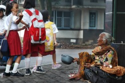 Indonesian parenting fail.  A child flips the middle finger towards a poor old woman who&rsquo;s just sit there begging for money.