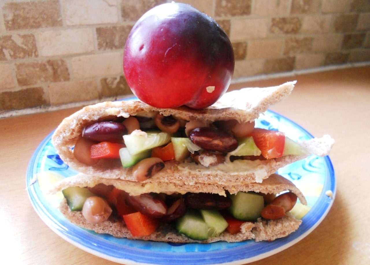 Lunch today - a wholewheat pitta with a thick spread of hummus, filled with chickpeas, soy beans, aduki beans, cucumber and red bell pepper. And a plum! :)