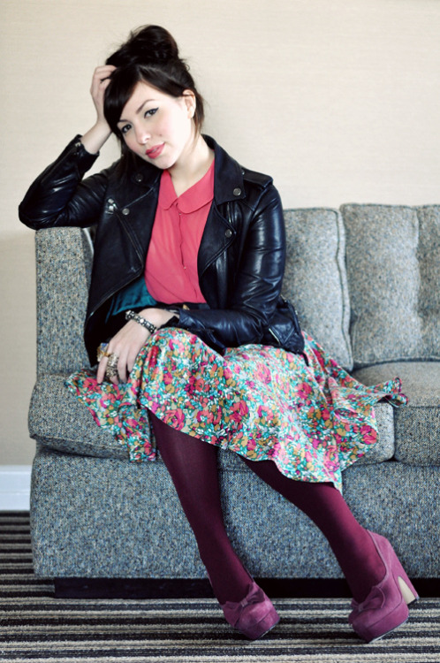 Purple tights with light colored flower print skirt, bright pink shirt and black leather jacket