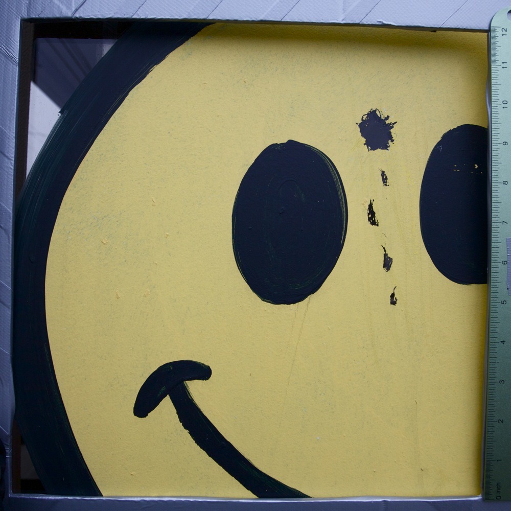Large yellow smiley face with scratched-out bullet hole and blood drip graffiti. N Lombard St.