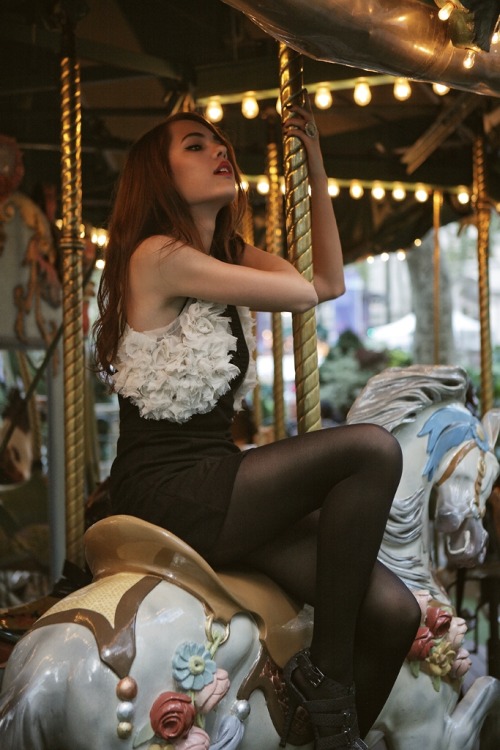 Black tights and short tight dress with white lace detail riding the merry-go-round