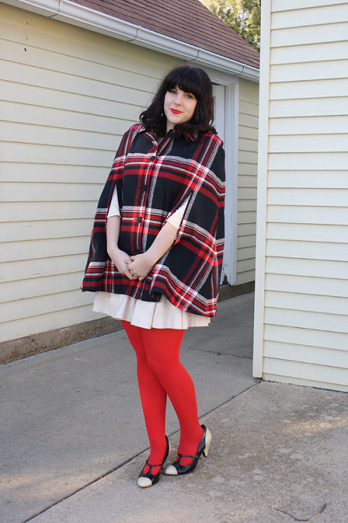 Bright red tights, beige dress and tartan cape