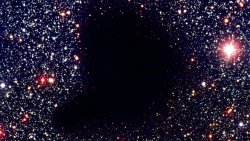 melbertg:  thenewenlightenmentage:  Hey, Who Ripped Open a Hole in the Universe? This eerie patch of blackness in the middle of a busy star cluster may look like a rather misshapen black hole, but it’s actually something even stranger. It’s also quite