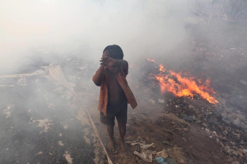 picturesoftheday: A child covered his eyes as he walked past burning trash in Dhaka, Bangladesh, Thu