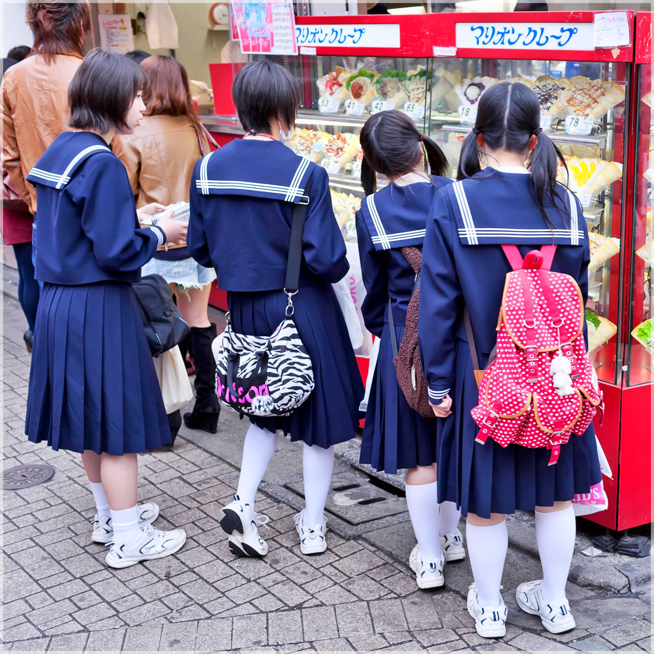 Harajuku schoolgirls waiting in line for crepes on Takeshita Dori.