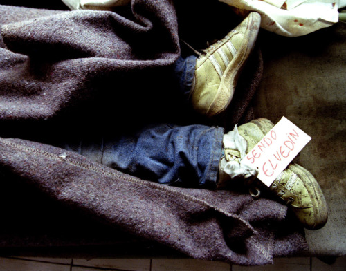 picturesofwar:
“ “The feet of 10-year-old Bosnian Muslim boy Elvedin Sendo, clad in grass-stained running shoes and marked with his name tag, protrude from under a blanket at a hospital morgue after his school came under a shelling attack in...