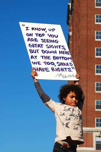 lipstick-feminists:[image description: photograph of a child holding a large sign above their head; 