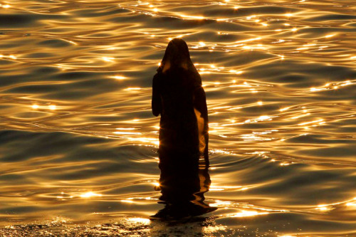 greenshirts-blog:An Indian Hindu woman offers prayers to the setting sun by the Arabian Sea in Mumba