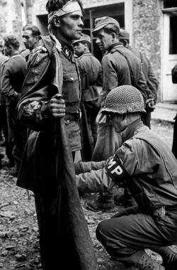 operationbarbarossa:  An American military policeman searching a captured German SS soldier - 1944  Photo by Robert Capa   Capa?!