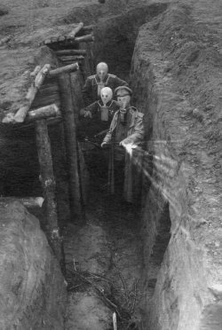  A Russian Officer and two soldiers wearing Zelinsky-Kummant gas masks, decontaminating the trenches after a gas attack exercise, 1915. 