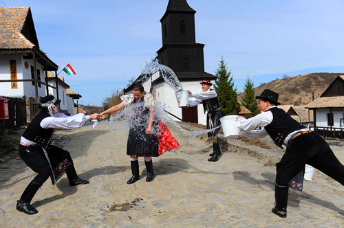 In Holloko, Hungary, a woman dressed in a traditional outfit is soaked by men during Easter celebrat