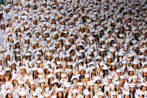 High school students raise their hands during graduation at Batasan Hills national high school in Qu