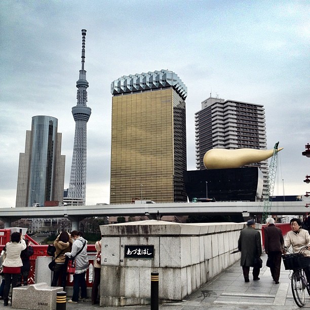 #PostModern skyline in #Tokyo #Japan, the Asahi Brewery Headquarters designed by #PhilippeStarck (1989) in Sumida, a golden #building and a black one resembling a beer glass with a golden flame at the top #architecture #architexture #archdaily...