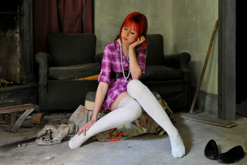 Red haired girl in white stockings doesn&rsquo;t know what a cozy fireplace means.