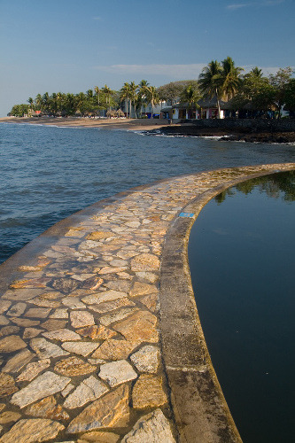 A rock path separates the sea from a salt water pool in El Salvador (by nantel).