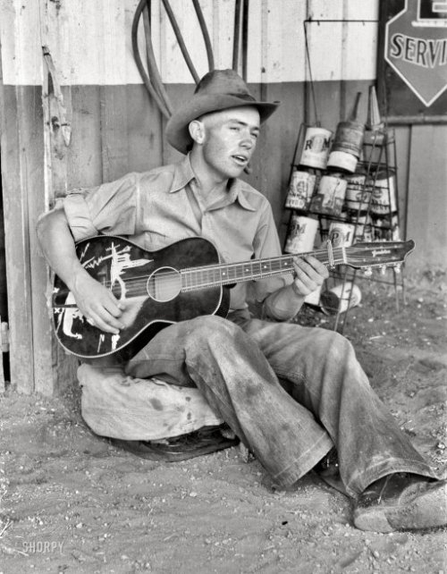 raggedglory: June 1940. Pie Town, New Mexico. “Farm boy playing guitar in front of the filling stati