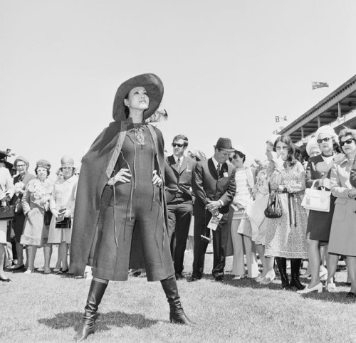 A Japanese model dressed in knee-length jumpsuit and cape draws a crowd at the Melbourne Cup, 1970. (via Strike a Pose – National Archives of Australia)