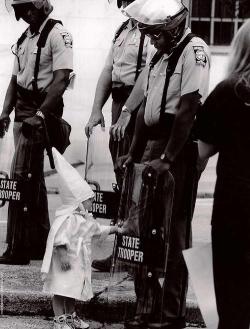 kemetically-ankhtified:  latinegro:  cwriting:  criminallyinnocent:  Here is a Georgia State Trooper in riot gear at a KKK protest in a north Georgia city back in the 80s. The Trooper is black. Standing in front of him and touching his shield is a curious