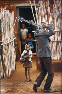 vintagegal:   apaana:  A worker on the farm plays the guitar with his daughter on a Sunday morning before he goes to work as a field hand, he works 60 hours a week for a salary of ฮ a month, South Africa ph. David Turnley, 1986  