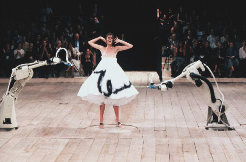 stopdropandvogue:  Shalom Harlow at Alexander McQueen Spring/Summer 1999 - No. 13  This show was inspired by the Arts and Crafts Movement and it ended with the model Shalom Harlow rotating on a turntable wearing a white dress being spray painted by two