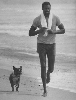 nbyay:  Wilt Chamberlain jogs on a California beach with his dog.