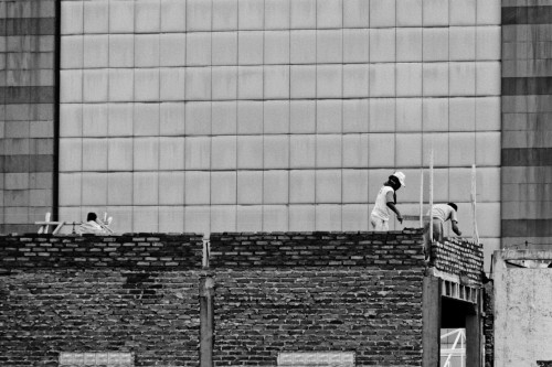 A bricklayer against a high rise