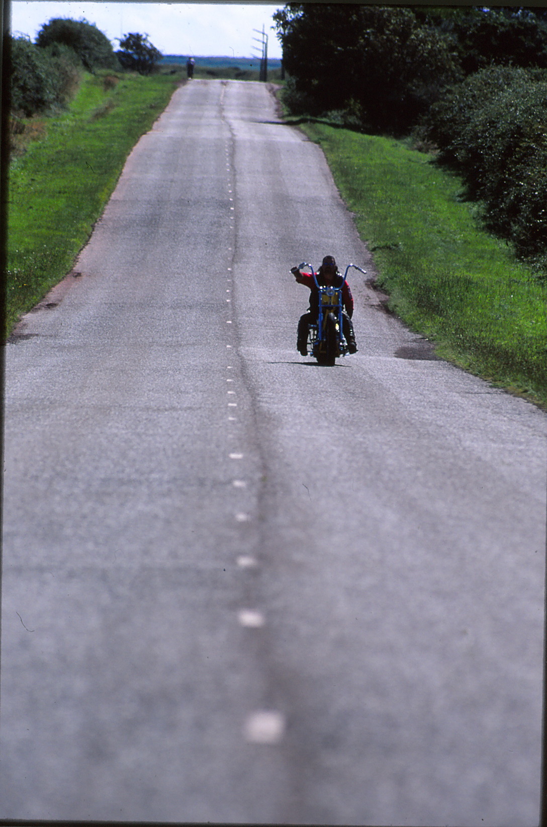 ‘Take The Long Road’. Welsh chopper guy Dick Tree rides his jockey shift chop along a road in Wales. This is why he’s on the left side of the road because that’s the way we do it in the UK.