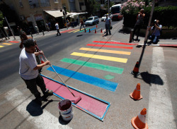     Municipality workers paint a pedestrian crossing in the colors of a rainbow flag before the start of the annual gay pride parade in Tel Aviv on June 8, 2012. (Amir Cohen/Reuters)  via LGBT Pride events)     
