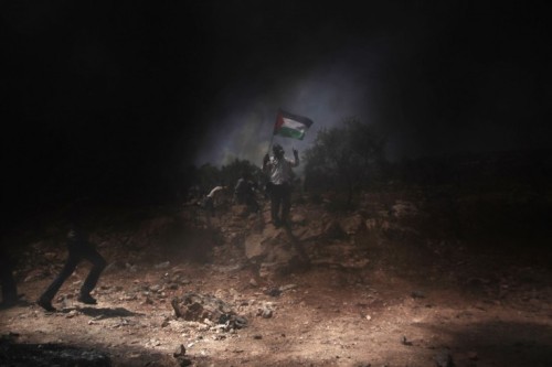 June 29, 2012. Palestinian protesters are seen through smoke from tires set on fire during clashes w