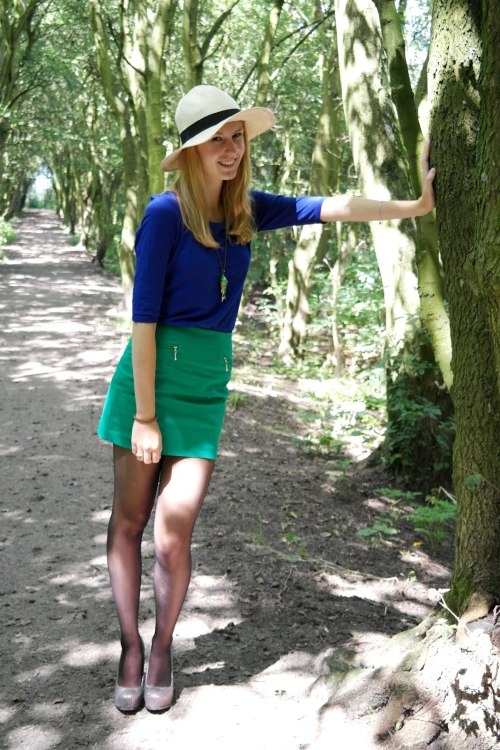 Green skirt and blue sweater with black sheer tights and straw hat