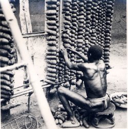 Ukpuru:   Photo Of An Igbo Man Tieing Yams Onto A Large Frame Made Of Stakes Inside