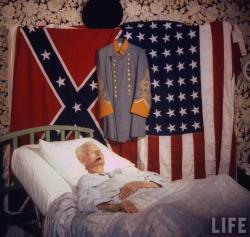 thecivilwarparlor:  Last Civil War Vet116-yr-old Walter Williams, last Civil War vet, in his bed w. a cigar in his mouth &amp; Confederate flag, Amer. flag &amp; uniform hanging on wall behind him. Location: Houston, TX, USDate taken: 1959 Photographer: