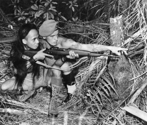 collective-history:Sergeant R Beaumont instructs a Dyak tracker in the use of modern firearms, Malay