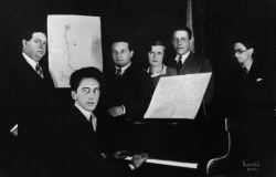 etund:  Jean Cocteau (seated) and Les Six: Darius Milhaud, an outline of Georges Auric, Arthur Honegger, Germaine Tailleferre, Francis Poulenc, and Louis Durey.