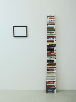 mianoti:  Aaron Kratch * Books stacked to human height, volumes checked out of the New York Public Library with their cover pages stamped to alert the reader that the book’s author committed suicide. 