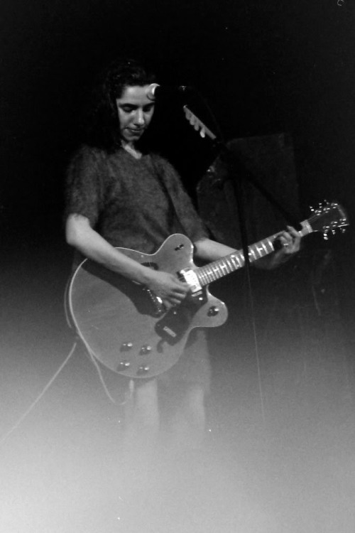 [image description: black and white picture from the 90s of the musician PJ Harvey performing playin