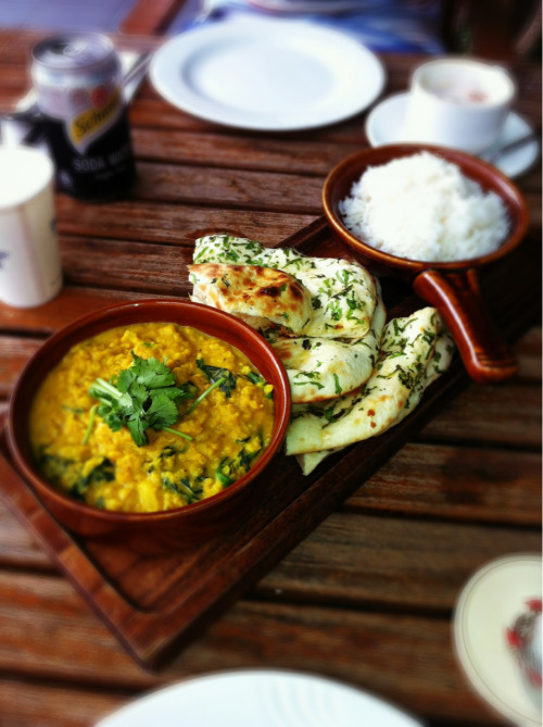 Sri Lankan curry outdoors on an overcast afternoon. Resting elbows on the chilly wood. Dishing hot c