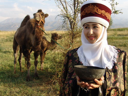 visitheworld:Kyrgyz woman wearing a traditional outfit with a bactrian camel and its calf, Kyrgyzsta