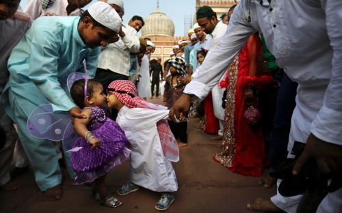 politics-war:A boy leans to rub noses with a girl as they are both dressed up for Eid al-Fitr prayer