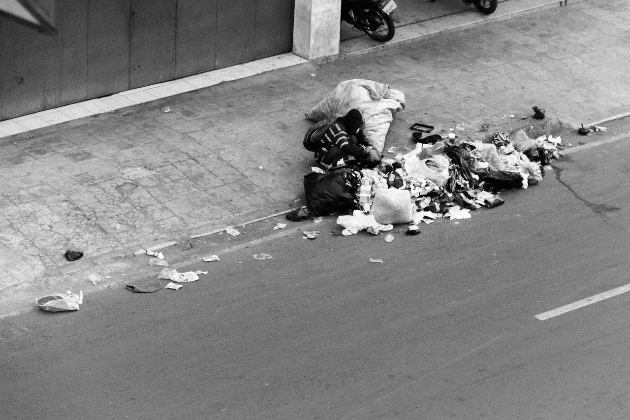 Man picking some stuff to keep/eat from a pile of trash.