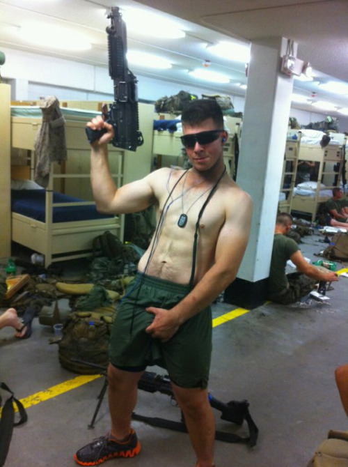 Shirtless military soldier grabbing his bulge though his shorts, in the barracks.