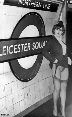Vintage air hostess from the 1960s shows a bit of leg, stockings and suspenders in the London Underground.